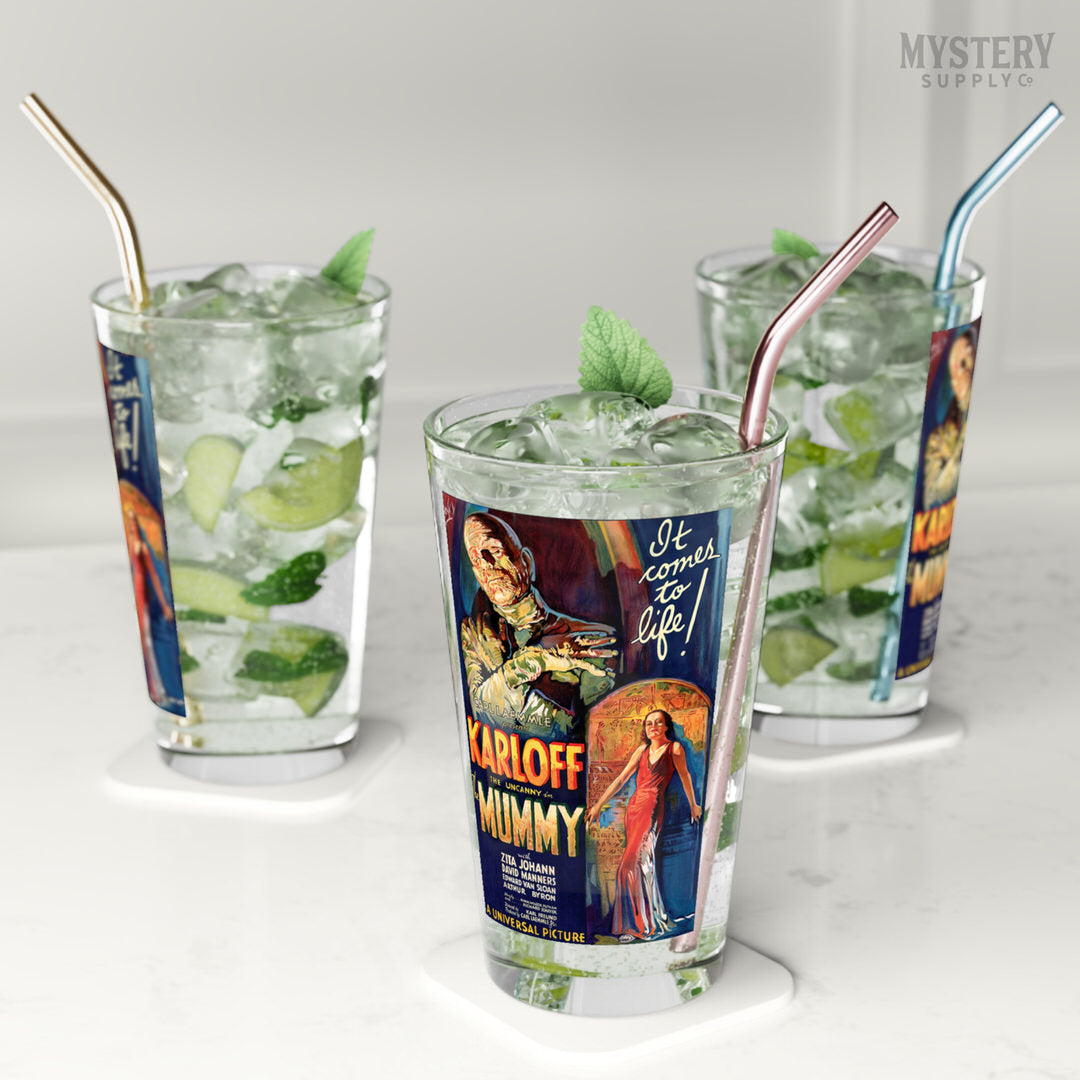 Three glasses with vintage movie poster design, filled with a mojito drink and ice, on a white surface. The Mummy 1932 vintage Boris Karloff horror monster movie poster reproduction 16oz clear pint glass home decor glassware from Mystery Supply Co. @mysterysupplyco