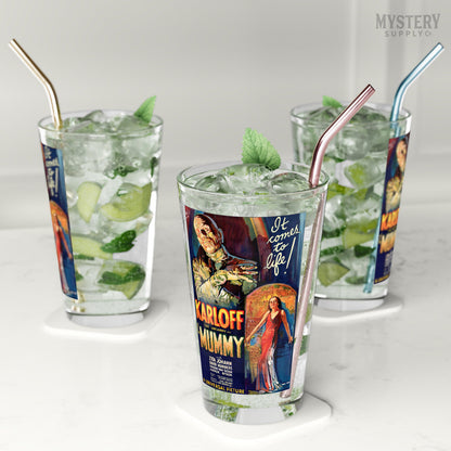 Three glasses with vintage movie poster design, filled with a mojito drink and ice, on a white surface. The Mummy 1932 vintage Boris Karloff horror monster movie poster reproduction 16oz clear pint glass home decor glassware from Mystery Supply Co. @mysterysupplyco